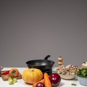 Studio composition of fresh vegetables and a frying pan, ideal for healthy cooking and recipe preparation.