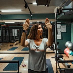 Pilates instructor guiding two women during a workout in a modern gym environment.